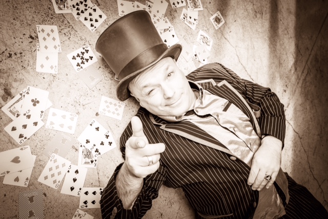 Zauberkünstler Bobby Wenzing inmitten eines Feldes aus Spielkarten